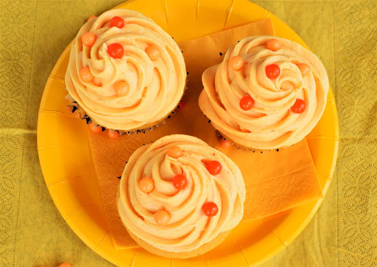 Pumpkin cupcakes on yellow plate.