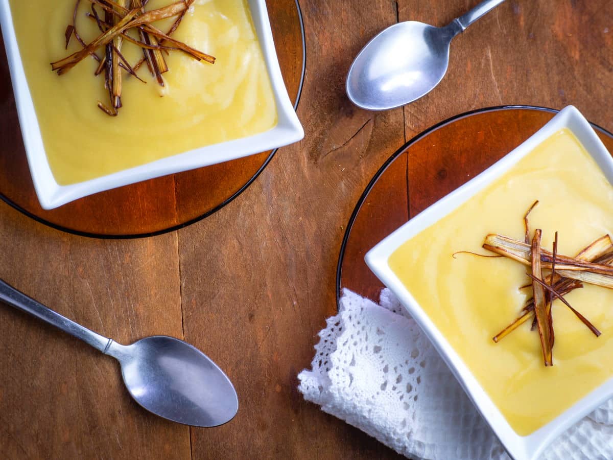 Leek and potato soup in white square soup bowls with spoons on the side.