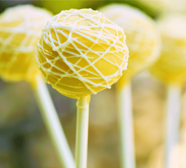 Lemon poppyseed cake pops with yellow frosting standing up.