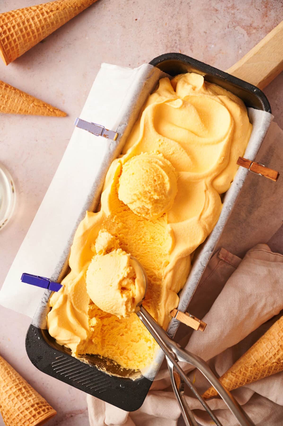 Mac and cheese ice cream in a loaf pan with an ice cream scoop.