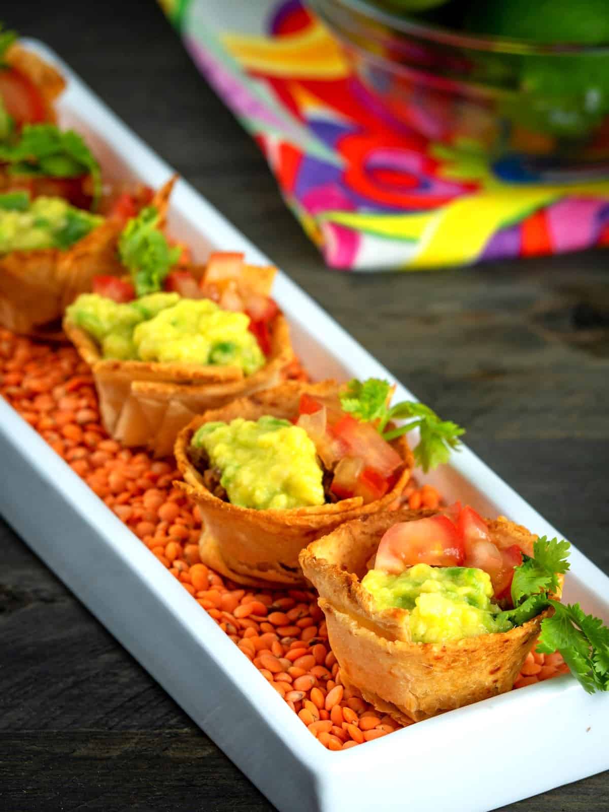 Baked taco cups in white dish with lentils.