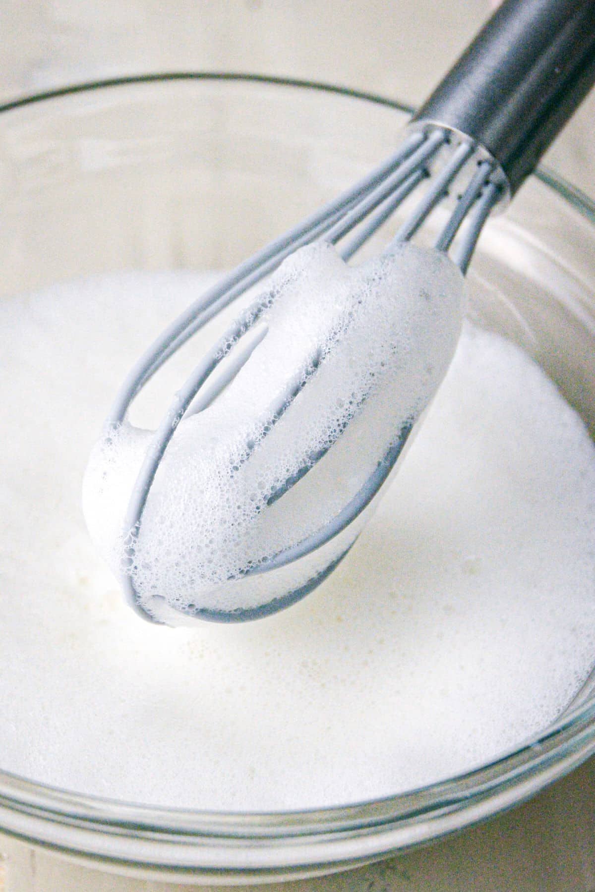 Milk frothed with wire whisk in a bowl.