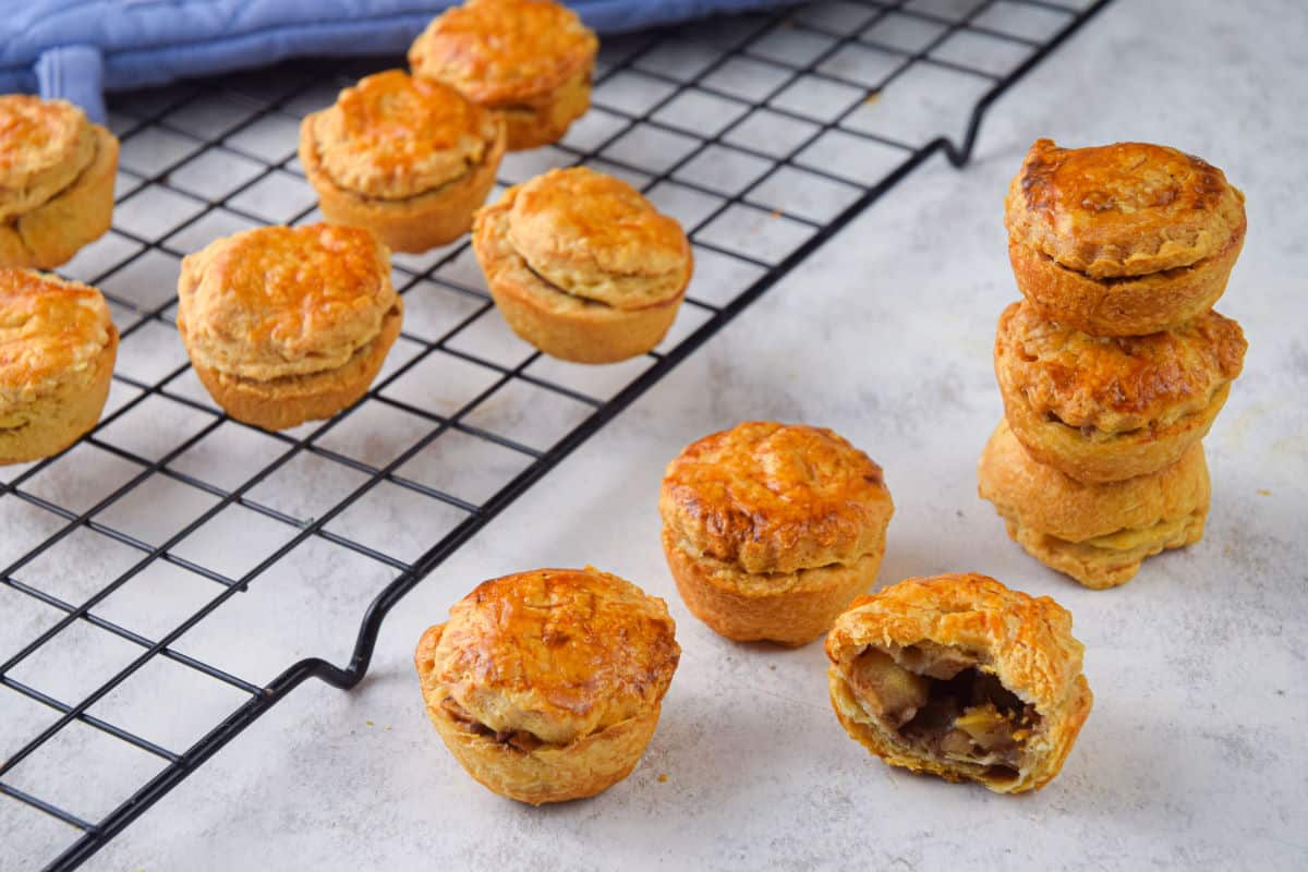 Mini apple pies on baking rack and stacked on the side.