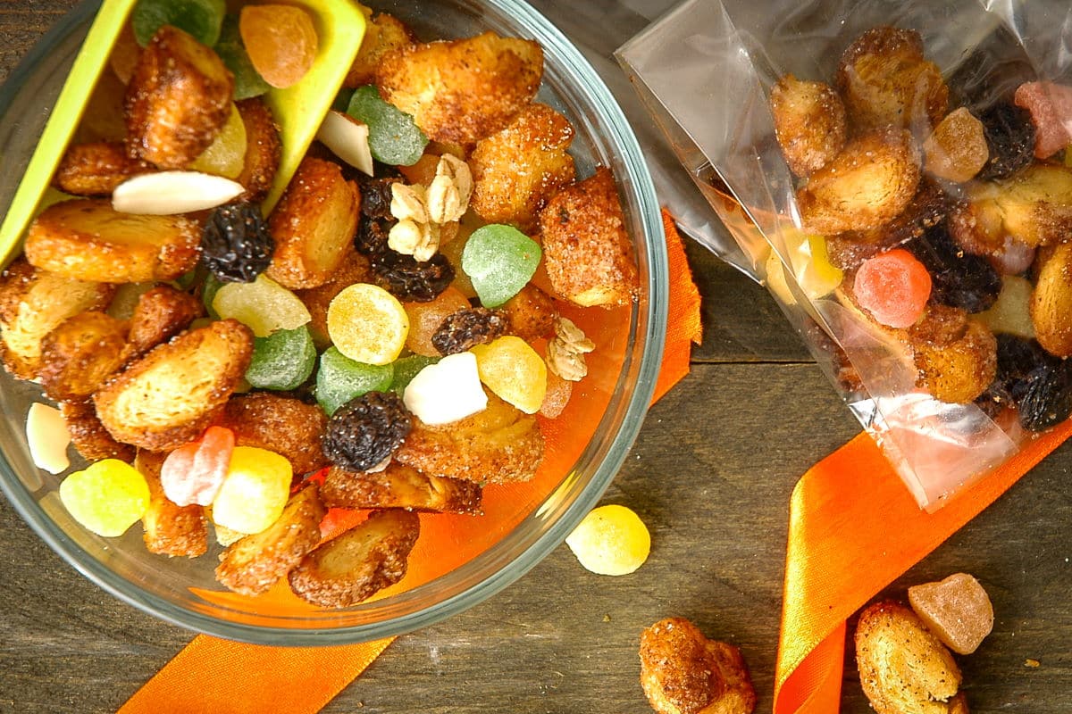 Churro snack mix in a bowl with a yellow scoop.