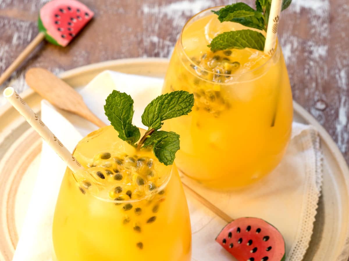 Passion Fruit & Ginger Mojitos Passion fruit mojitos in glasses with watermelon swizzle sticks.