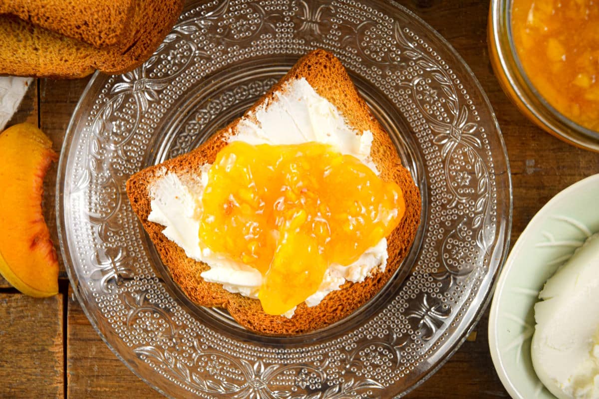 Peach freezer jam and cream cheese on a piece of toast.