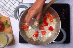 Red bell pepper, onion and garlic in pot.