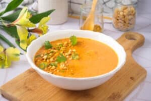Peanut butter soup in white bowl on cutting board.