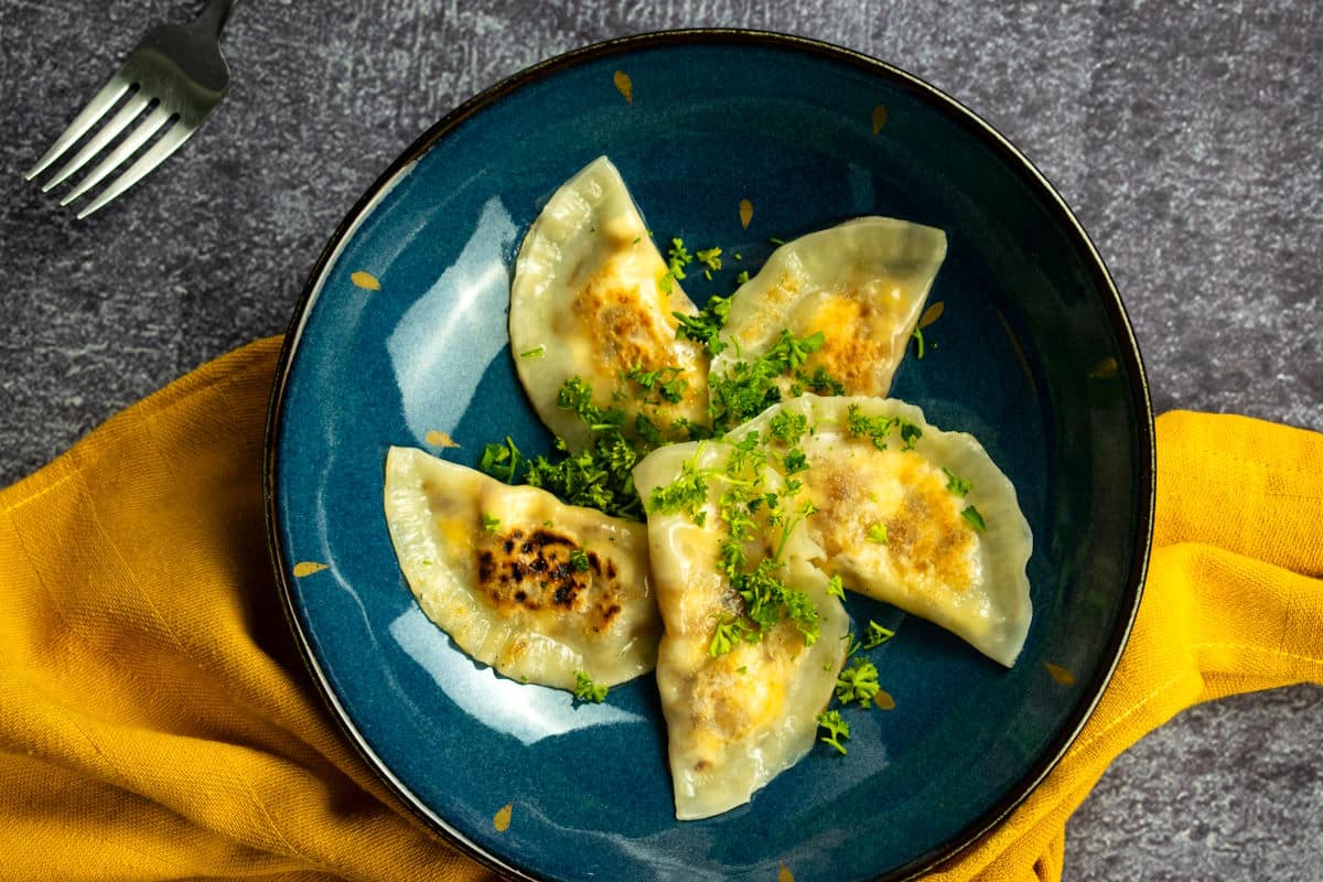 Pierogies on blue plate with fresh parsley.