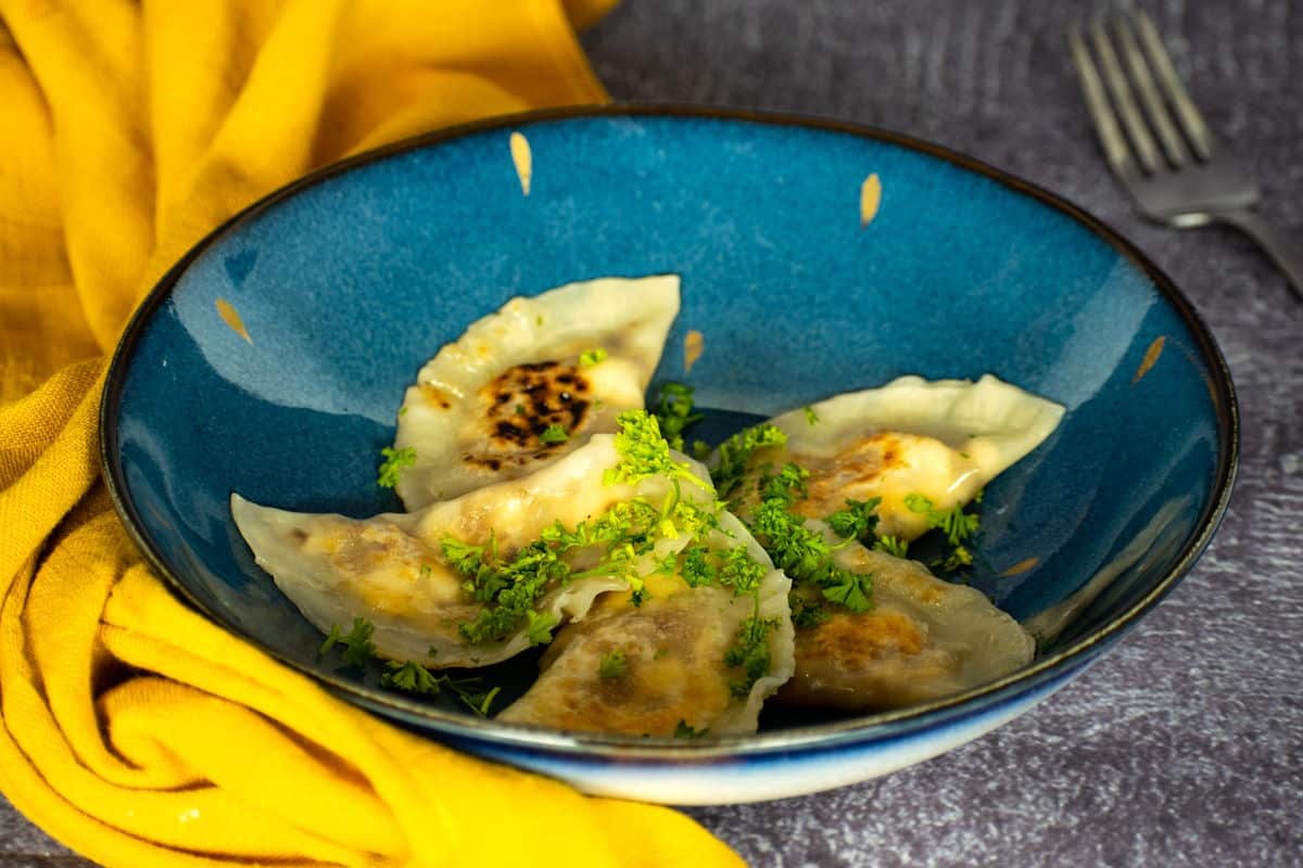 Pierogies on blue plate with freshly chopped parsley.
