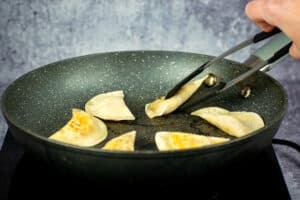Pan with golden pierogies in it.