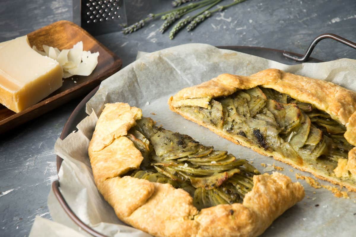Baked potato galette on parchment, Parmesan cheese on the side.