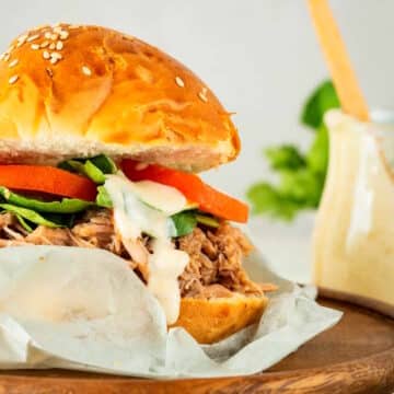 Pulled pork burger with special sauce on parchment.