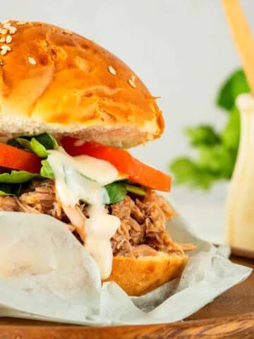 Pulled pork burger with special sauce on parchment.
