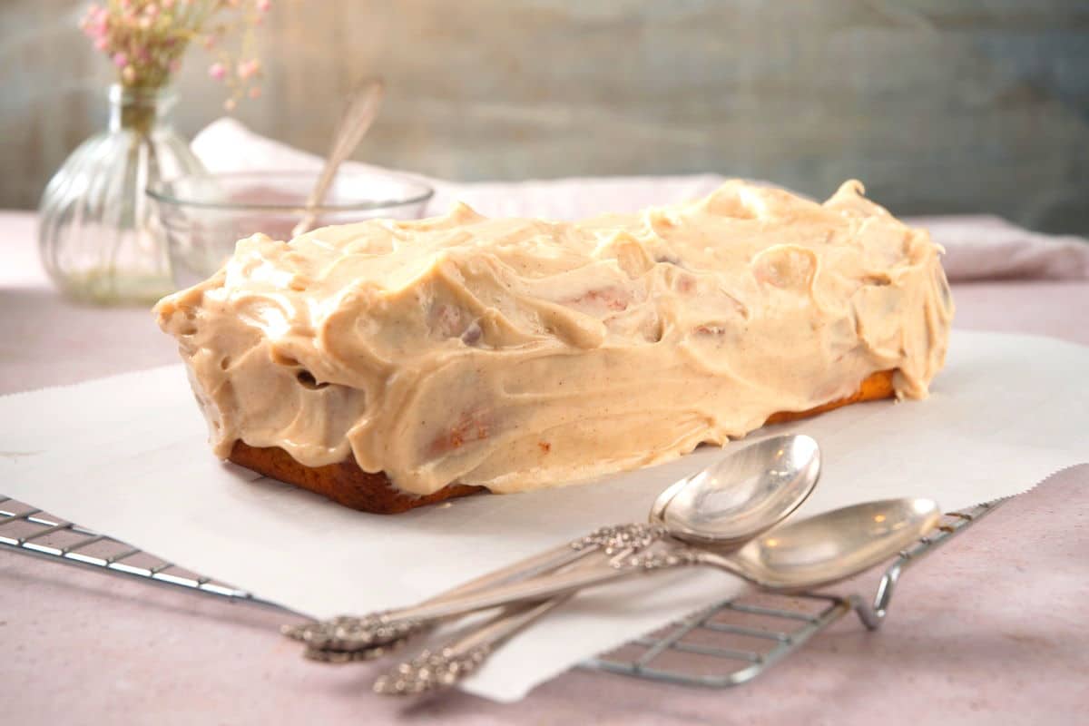 Frosted pumpkin bread loaf on parchment-lined baking rack.
