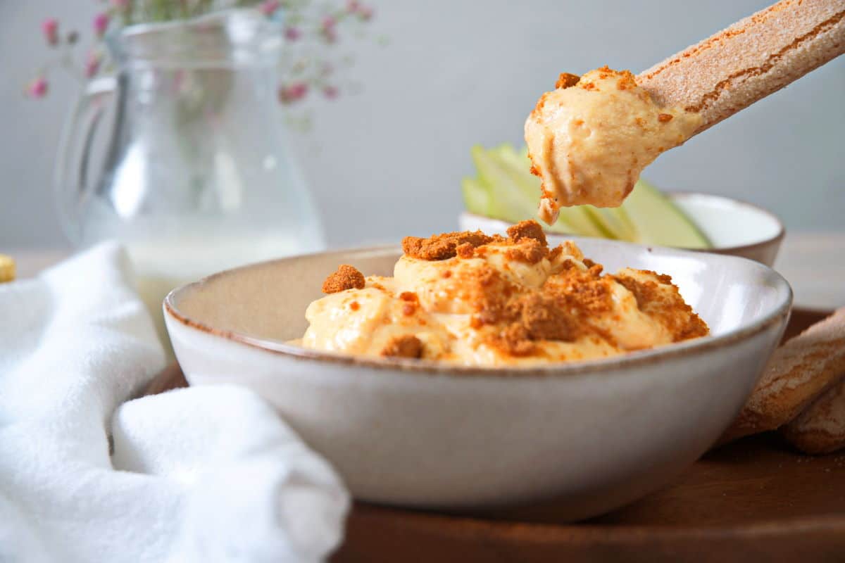 Pumpkin fluff dip with a biscuit dipping into the bowl.