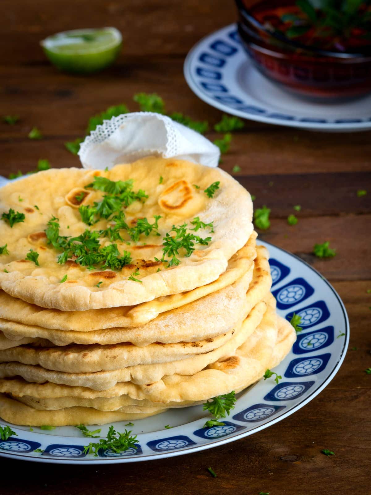 Pumpkin & Garlic Naan Bread 2 Pumpkin naan bread stacked on a decorative plate with freshly chopped parsley.