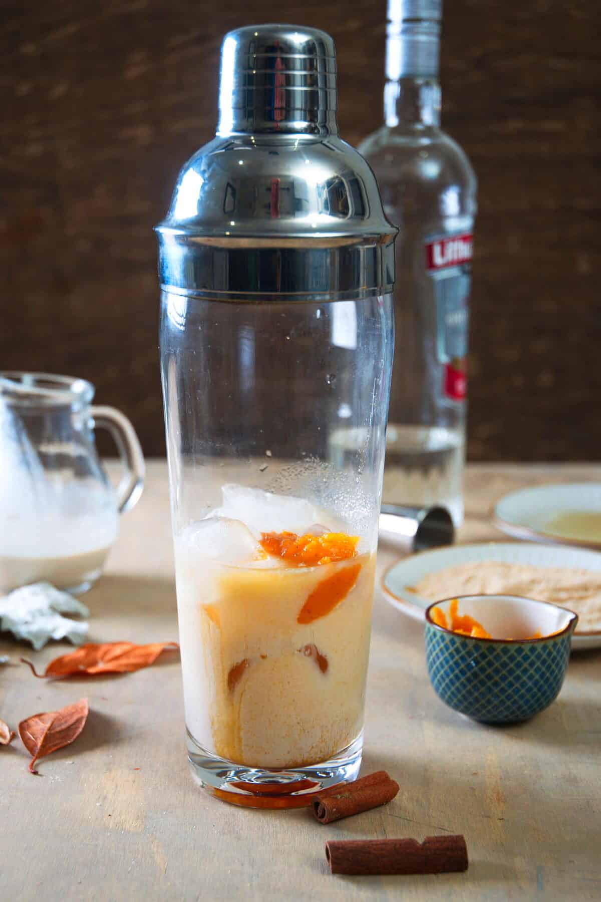 Cocktail shaker filled with ice and pumpkin martini ingredients.
