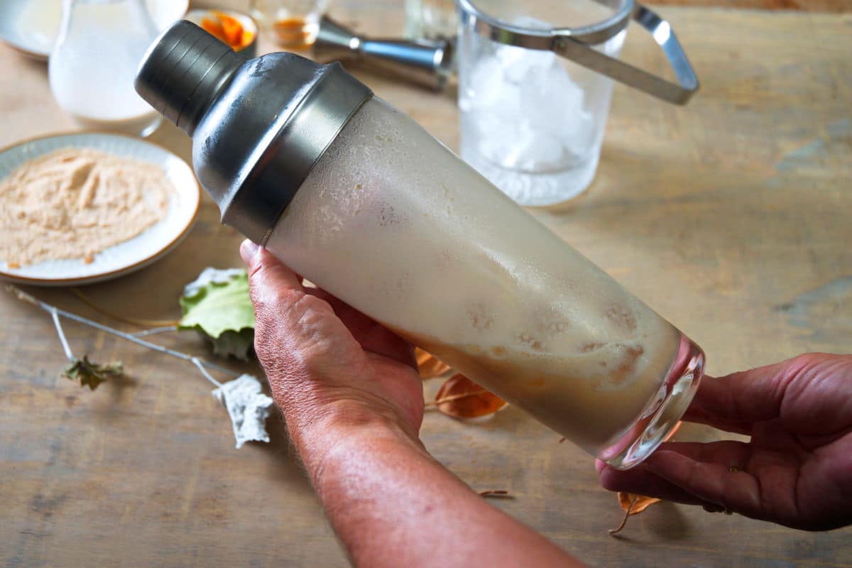 Cocktail shaker filled with pumpkin martini and ice.