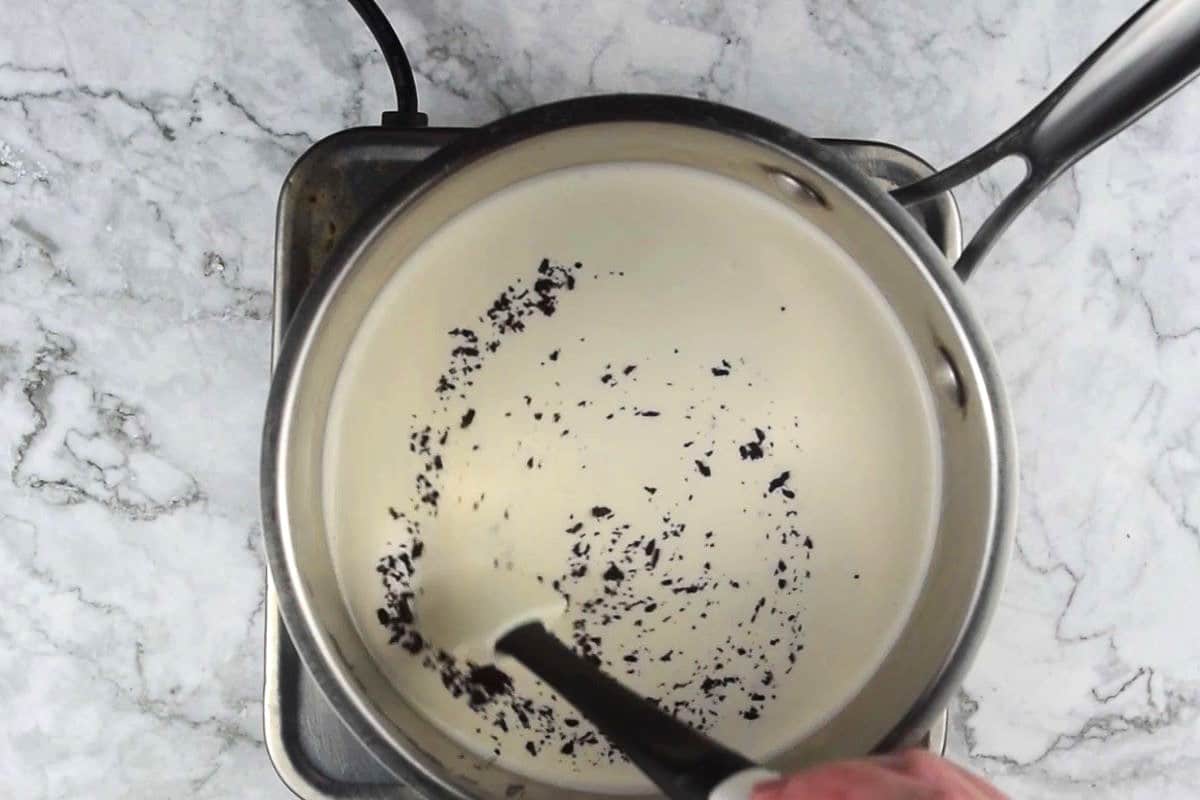 Heavy cream and vanilla powder in pot.
