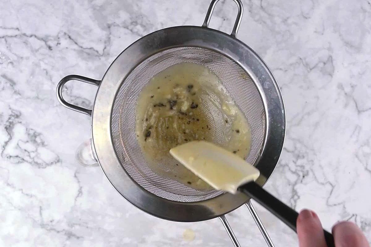 Crème Brûlée custard straining through mesh strainer.