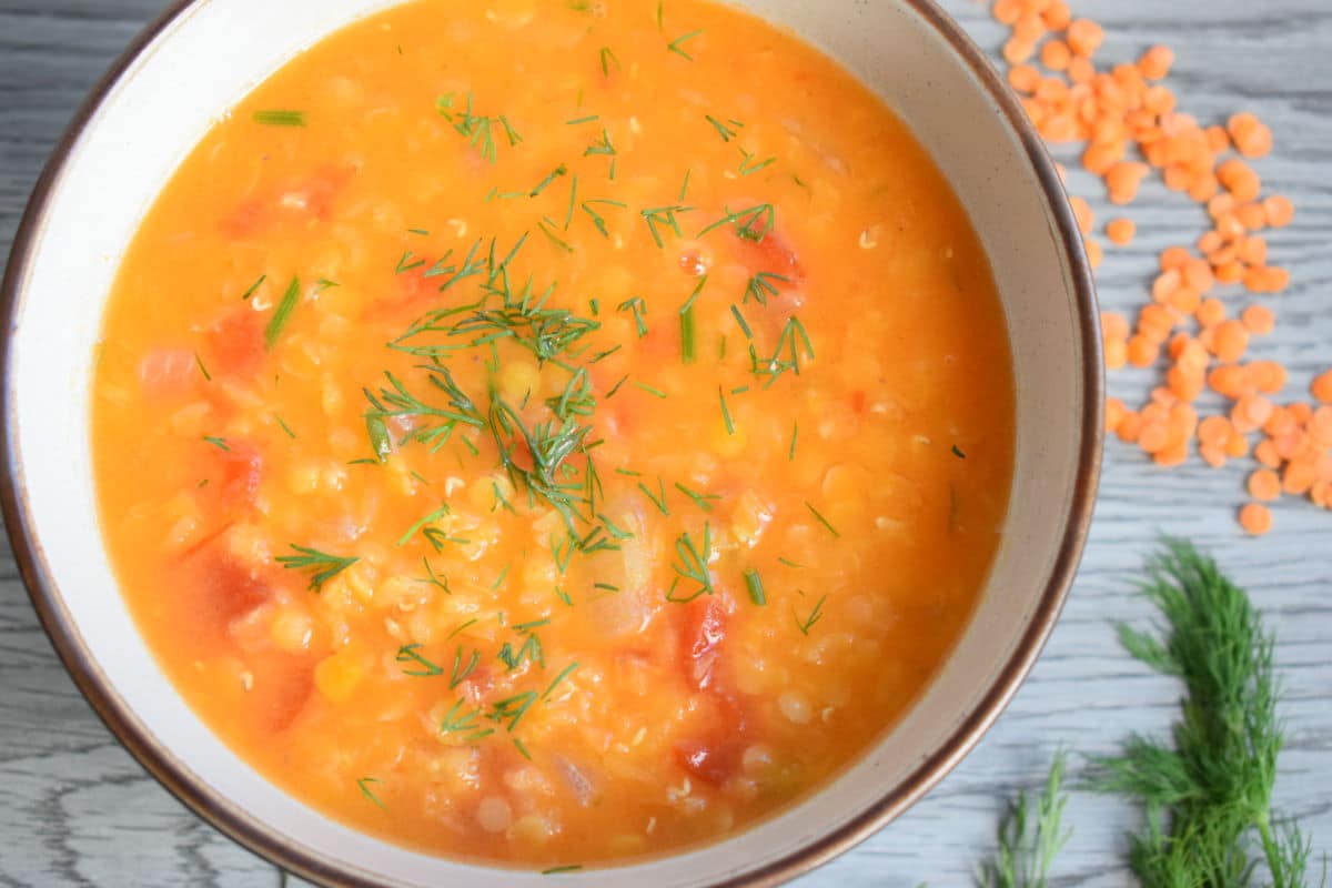 Red lentil soup in a bowl on grey wood background.