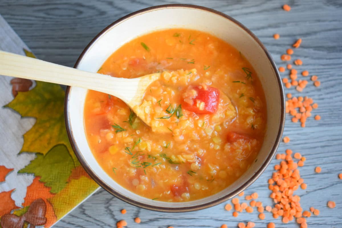 Red lentil soup in a bowl with a spoon.