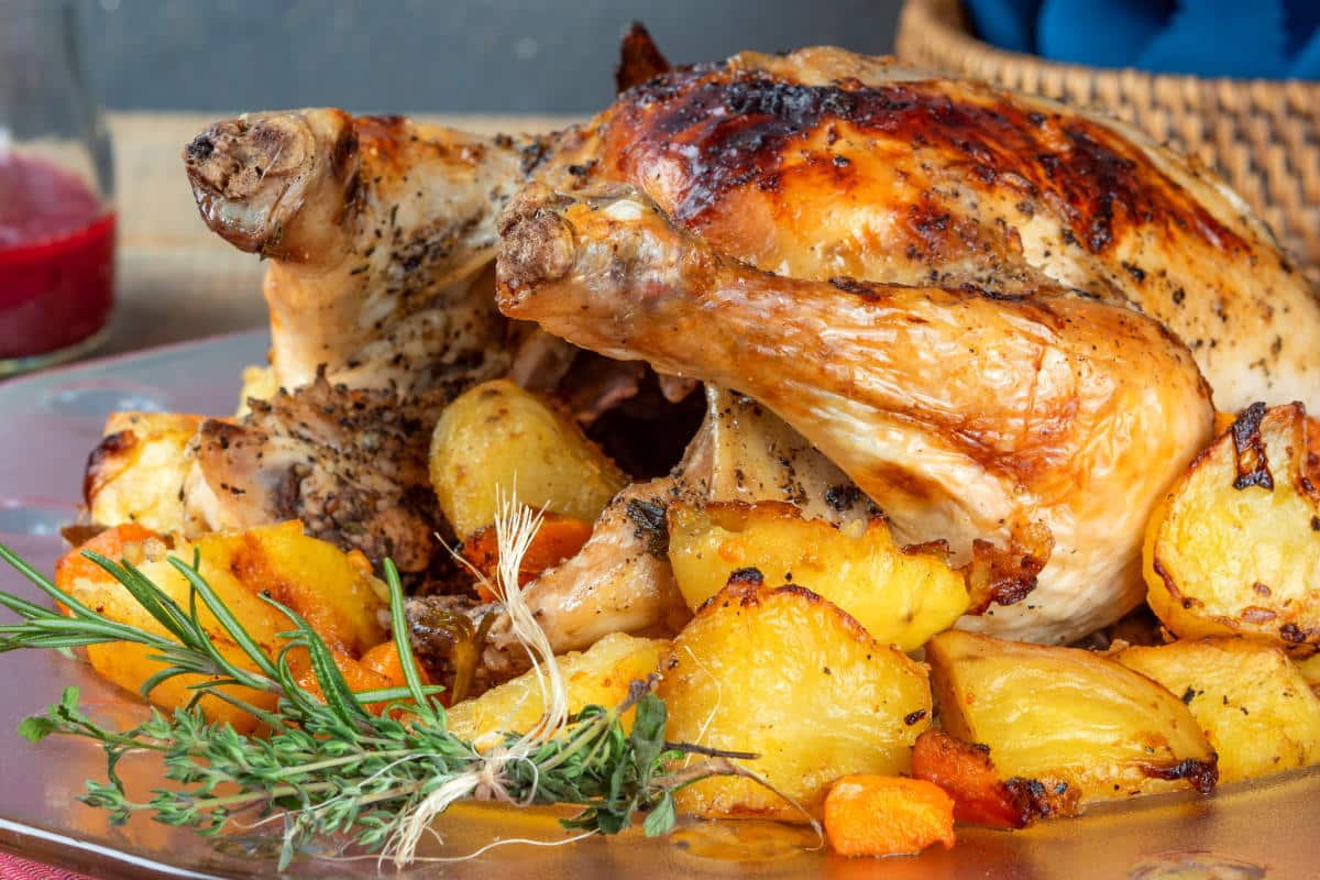 Roasted Chicken and vegetables on a serving plate with blackberry gravy in the background.