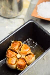 Roasted garlic head in loaf pan.