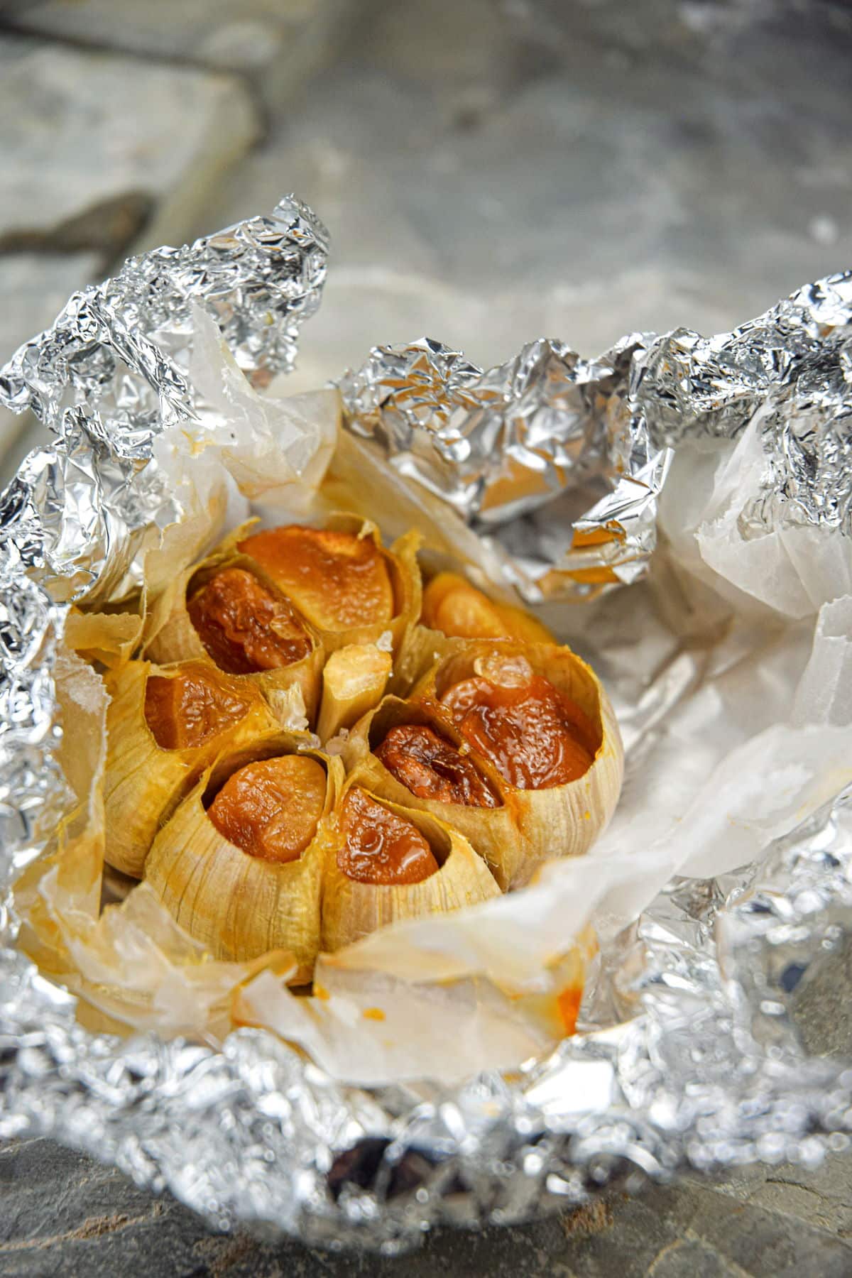 Roasted garlic head in opened foil pouch.