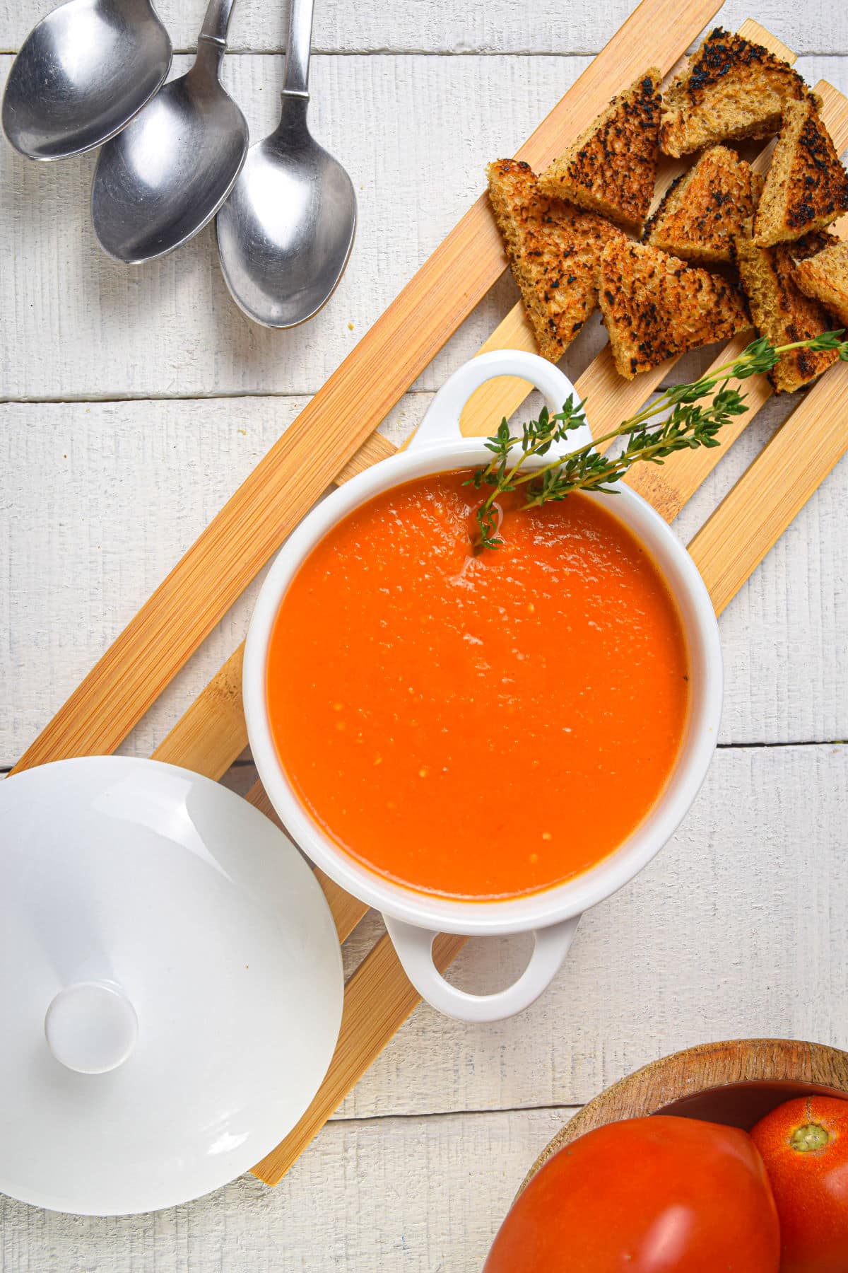 Roasted tomato soup in a bowl with fresh thyme and toast points.