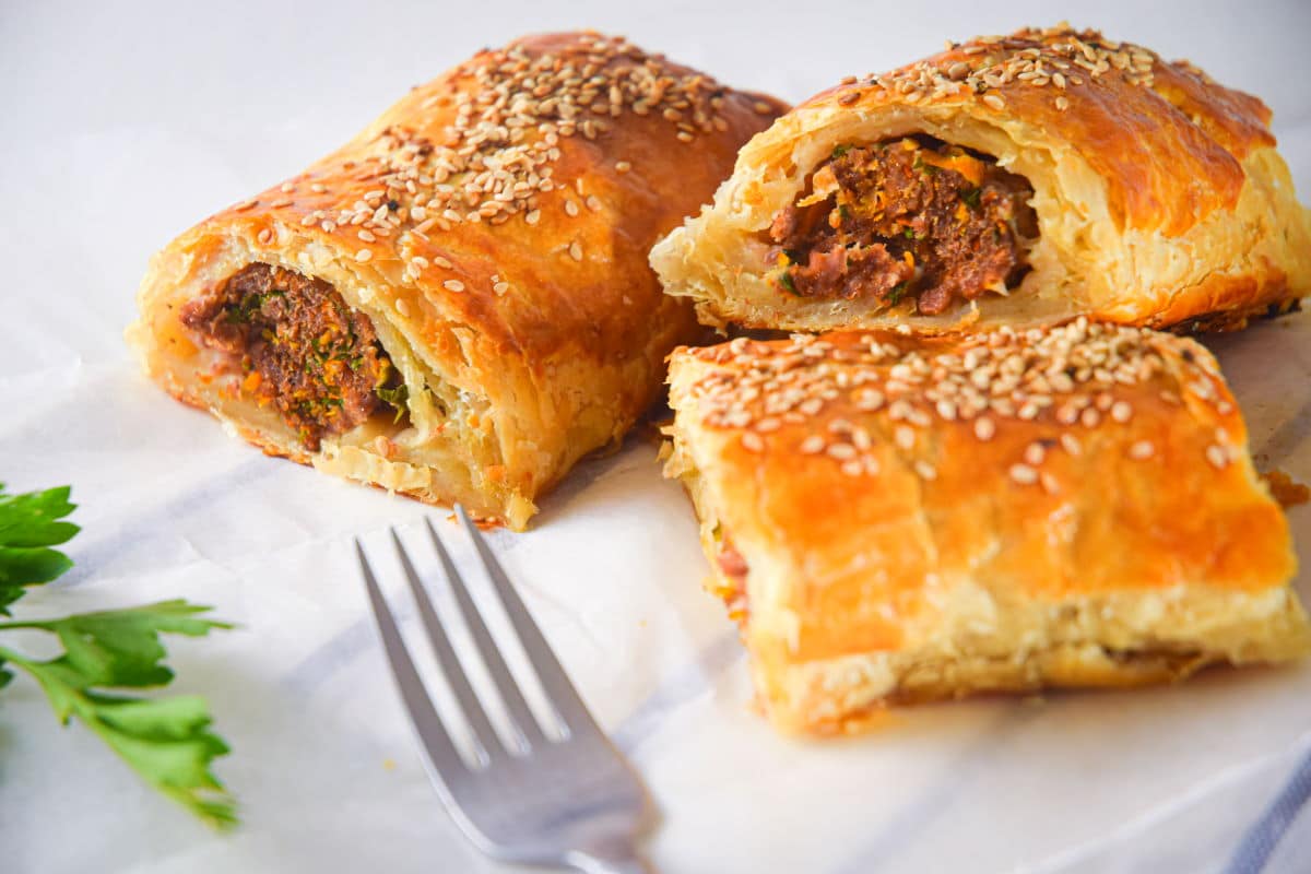 Sausage rolls cut open on parchment.