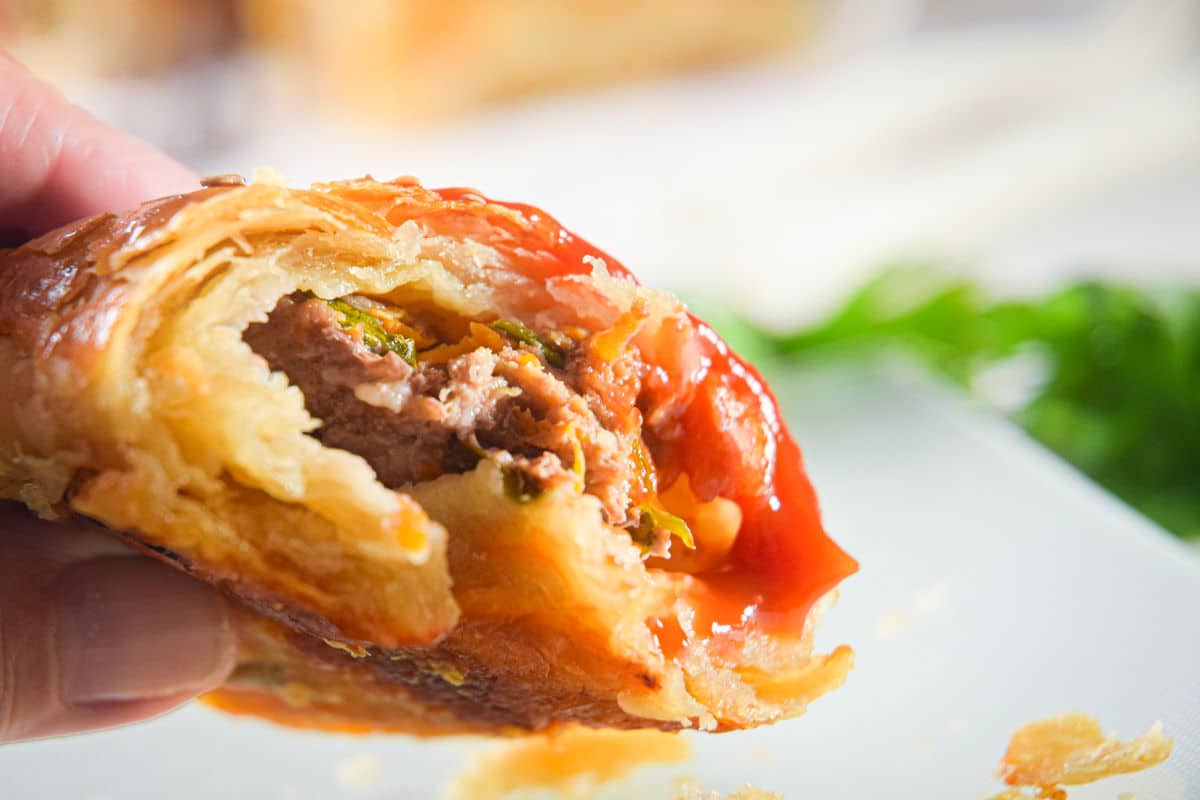 Sausage roll cut open with ketchup.