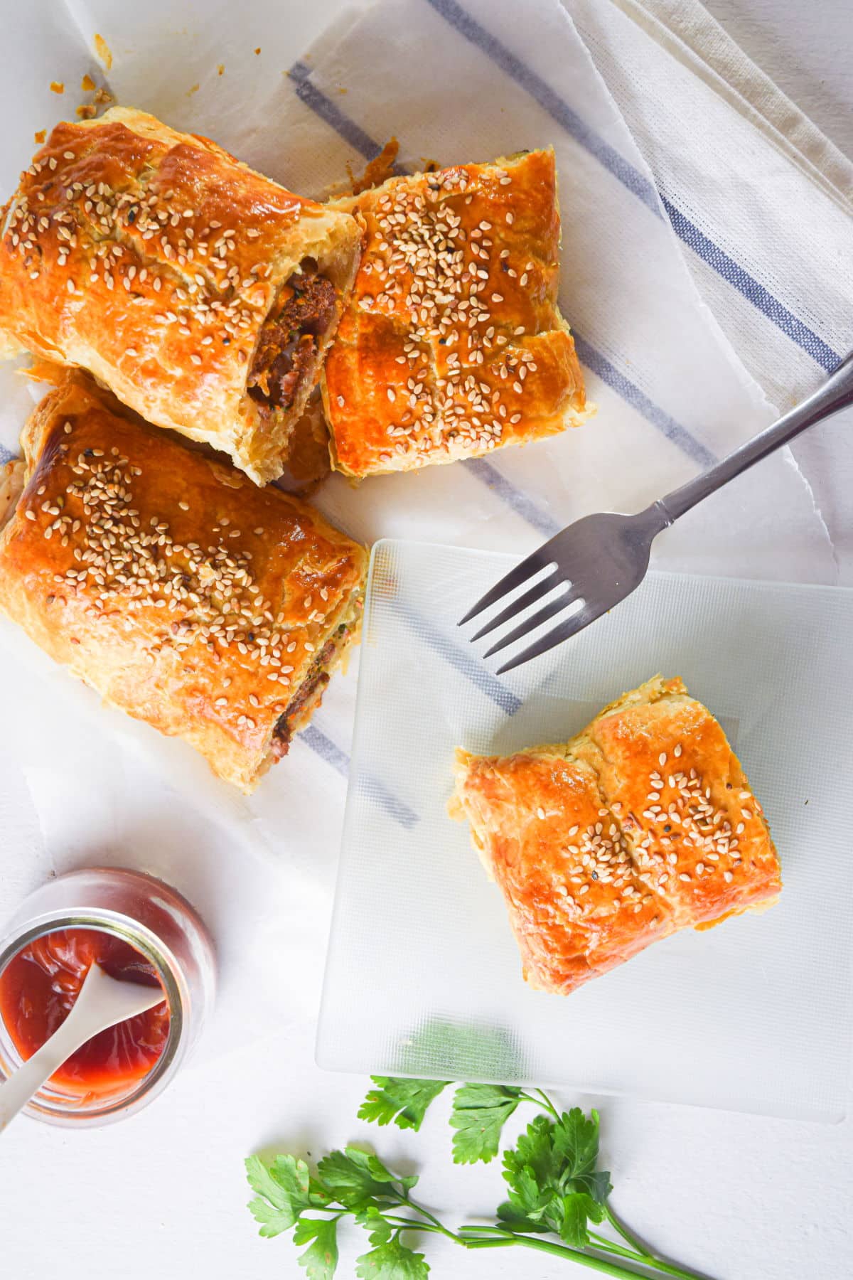 Sausage rolls with a fork, dipping sauce and cilantro.