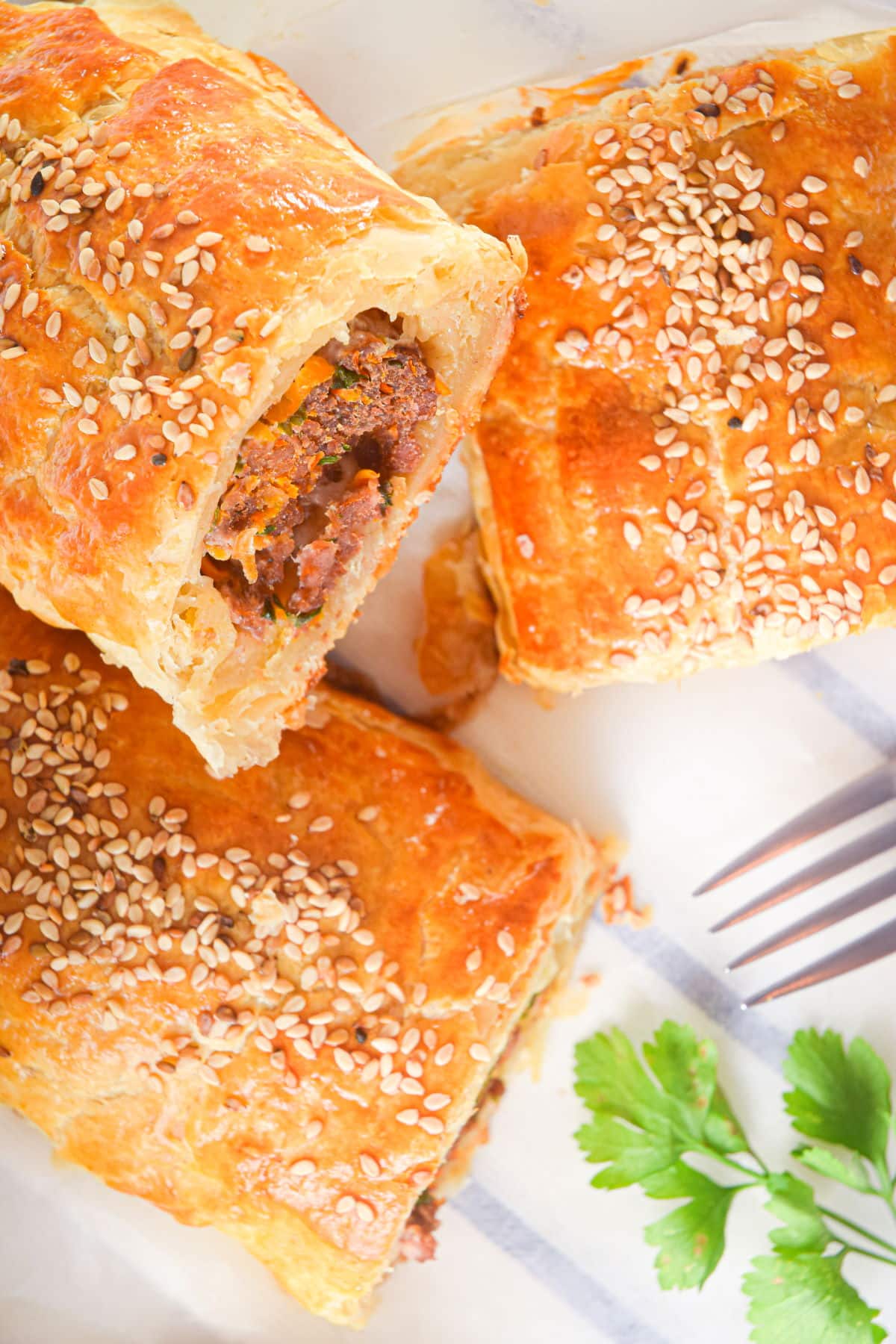 Baked sausage rolls with a fork and cilantro.