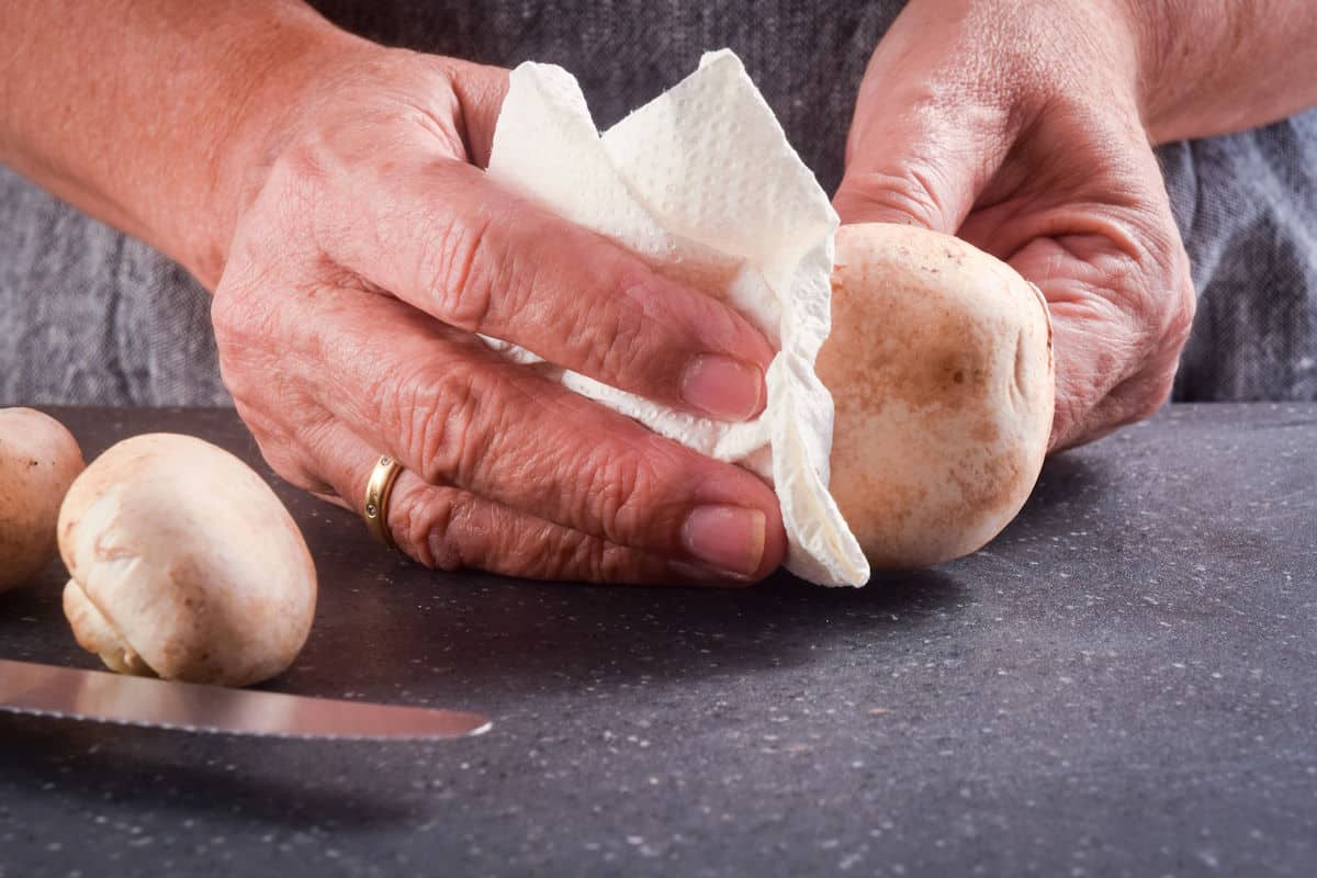 Mushrooms getting cleaned with paper towel.