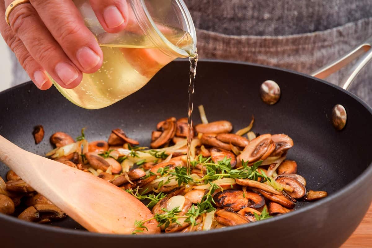 Sautéed mushrooms in pan with onions, thyme and white wine.