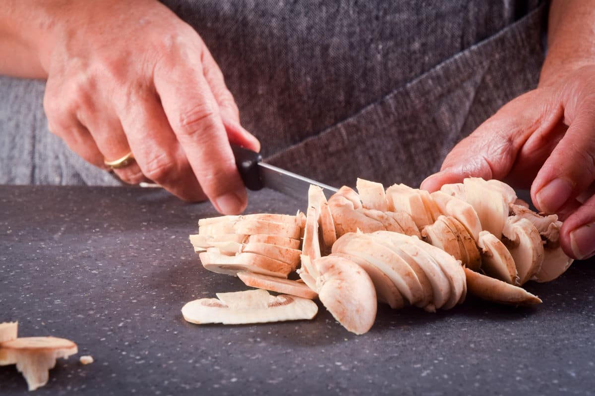 Button mushrooms sliced with knife.