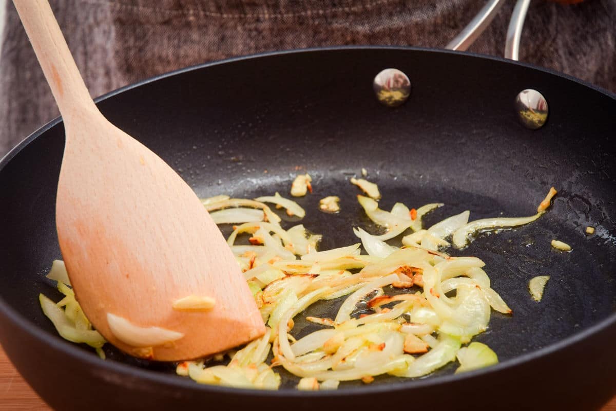 Sliced onions cooking in pan.