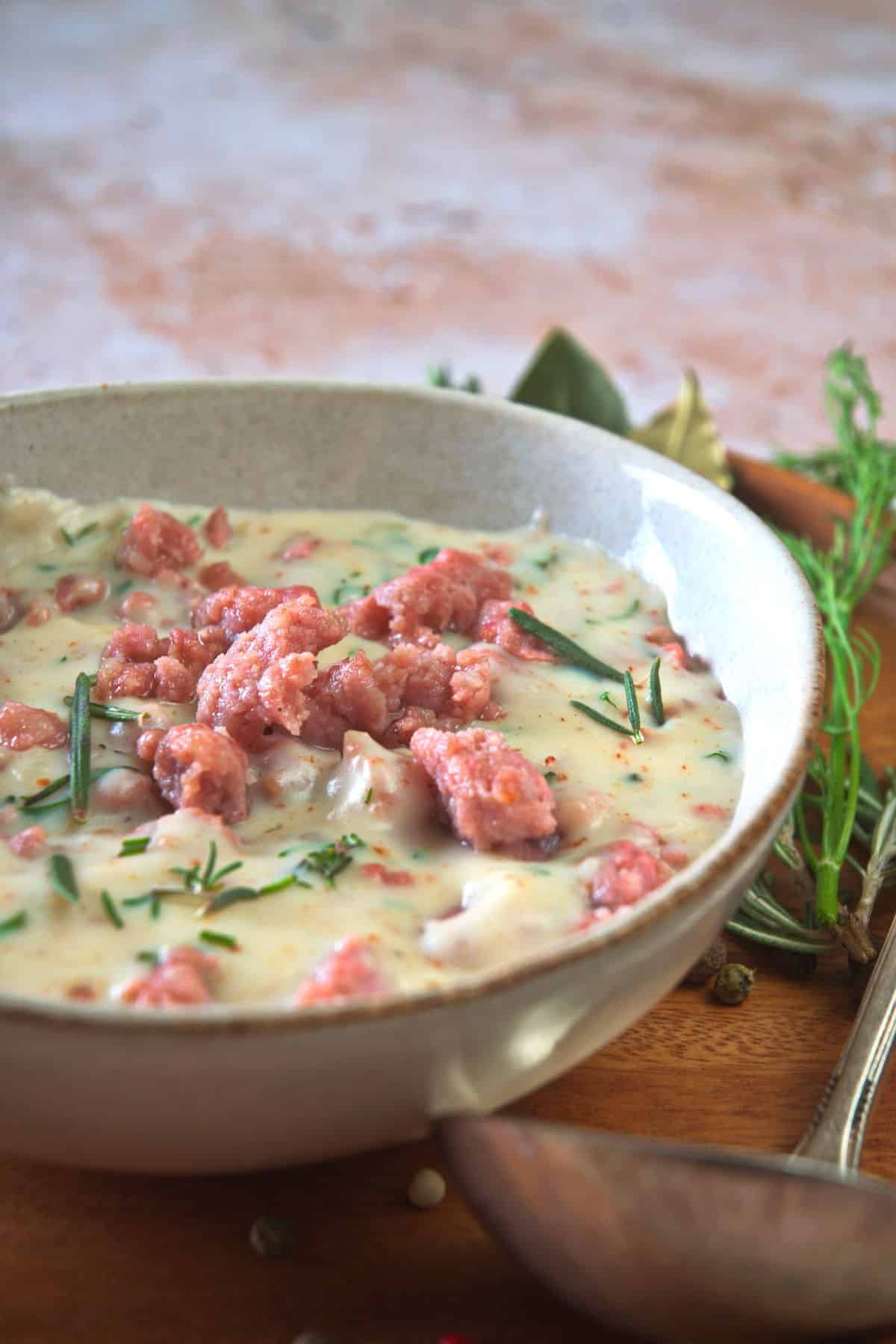 Sawmill gravy in a white bowl and a gravy spoon on the side.