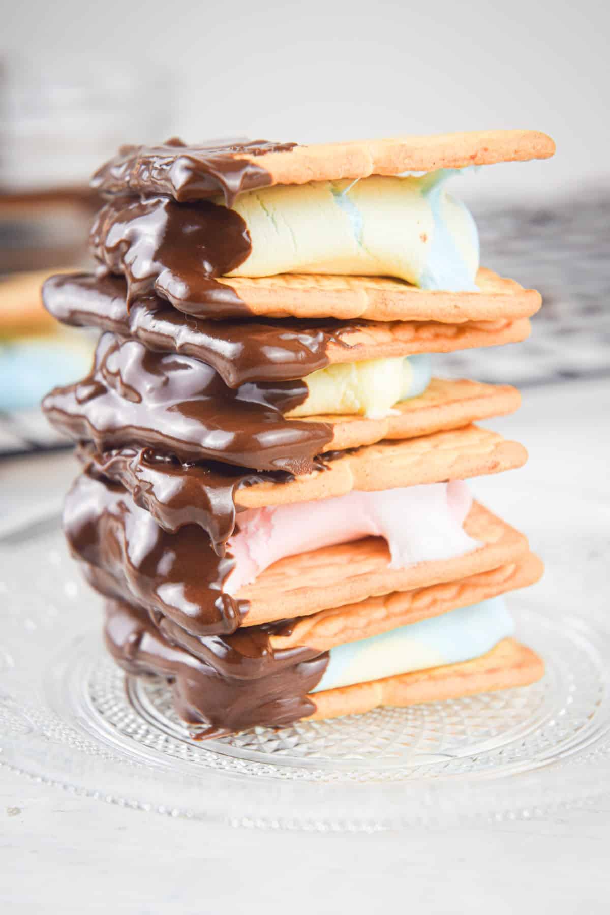 Stacked s'mores on a clear glass plate.