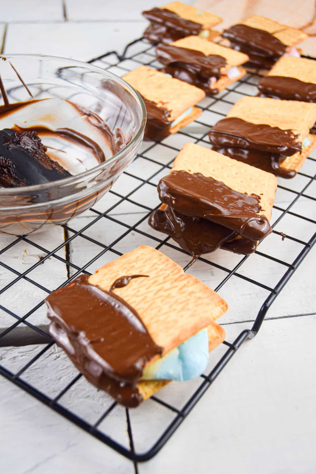 Skillet s'mores cooling on wire rack with bowl of melted chocolate.