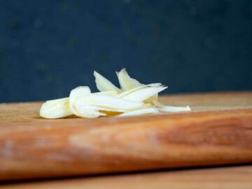 Sliced garlic on cutting board.