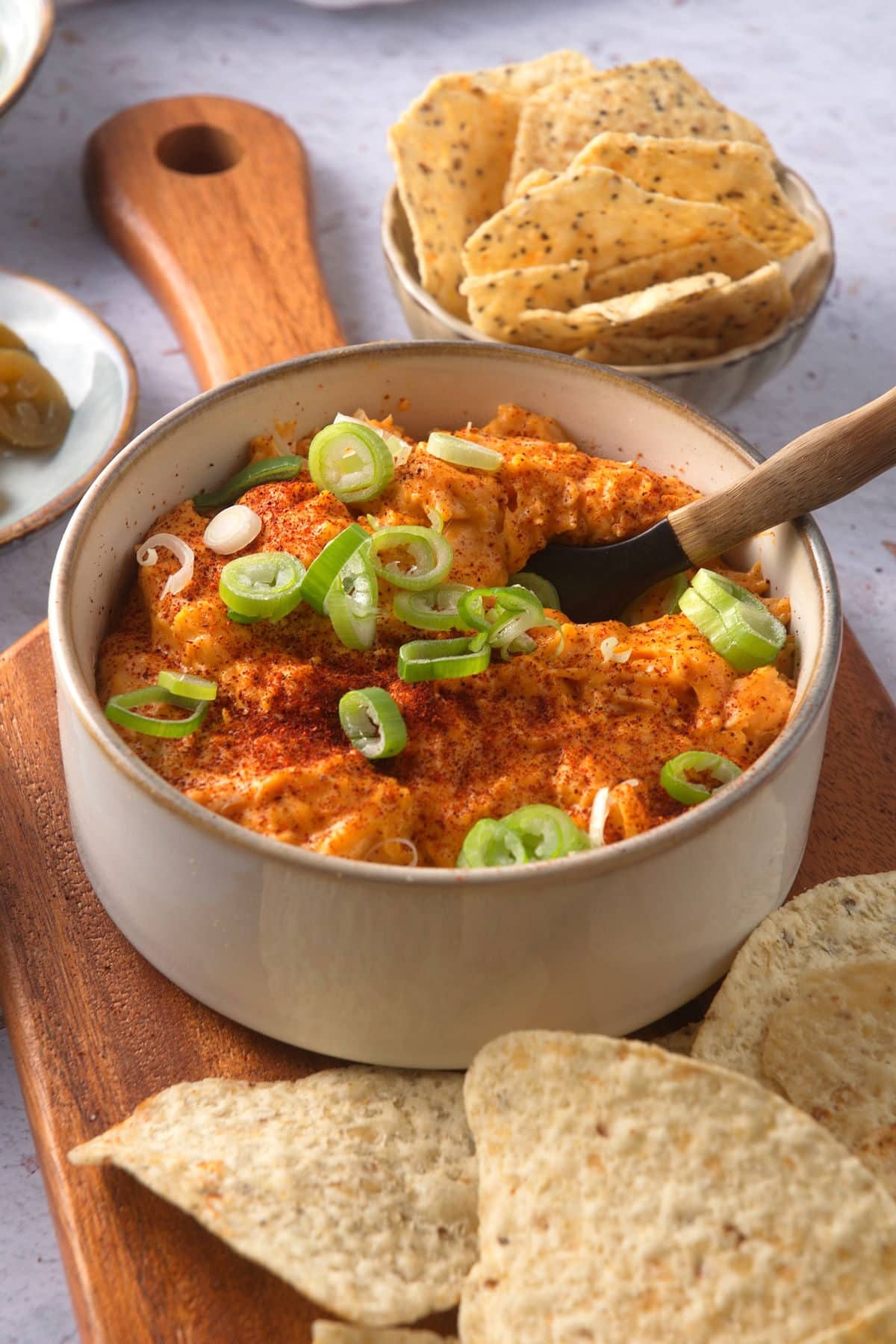 Buffalo chicken dip in white dish with chips on the side.