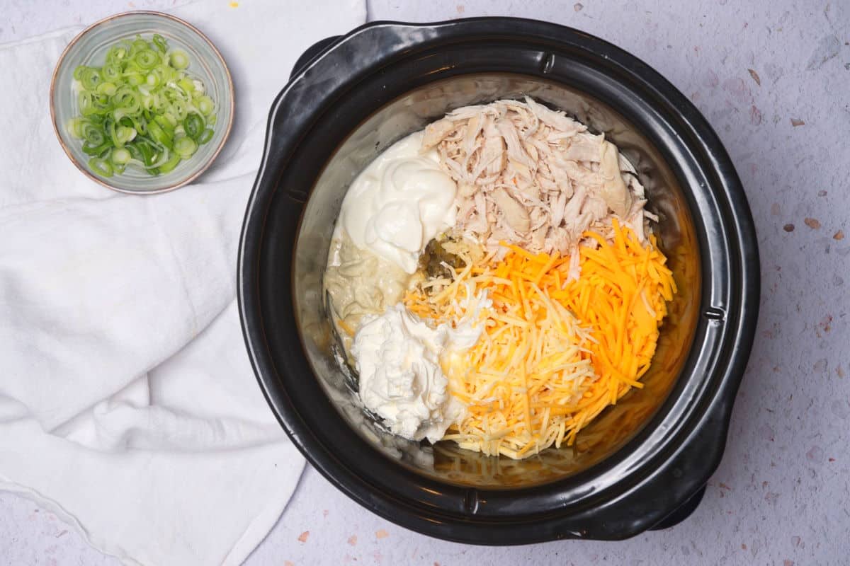 Slow cooker filled with buffalo chicken dip ingredients.