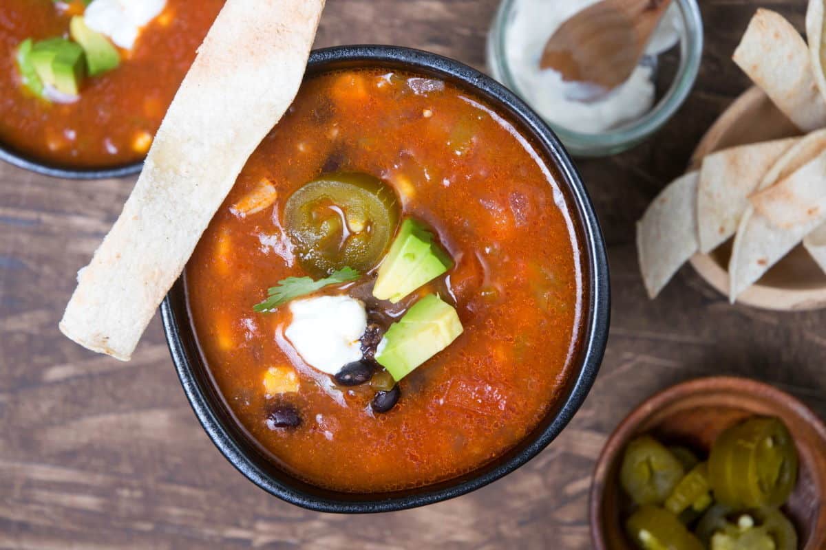 Mexican soup in black bowls with tortilla strips.