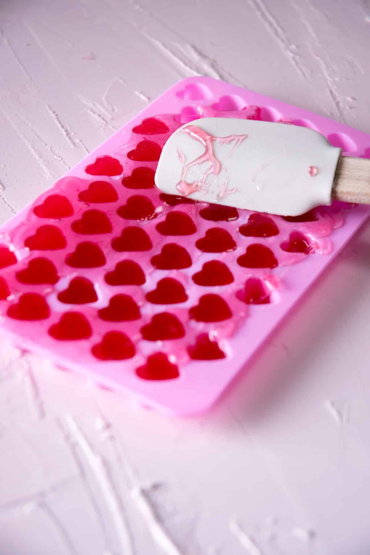 Strawberry candy mixture spread out in a pink heart mold.