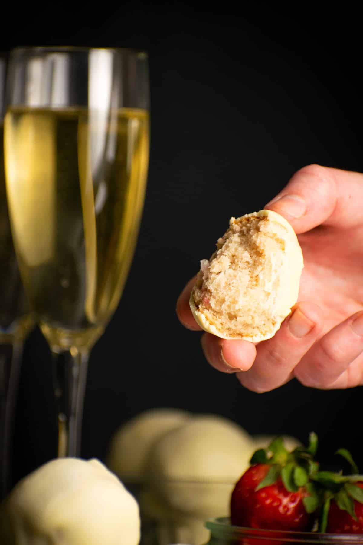 Strawberry champagne cake ball cut open in a hand.