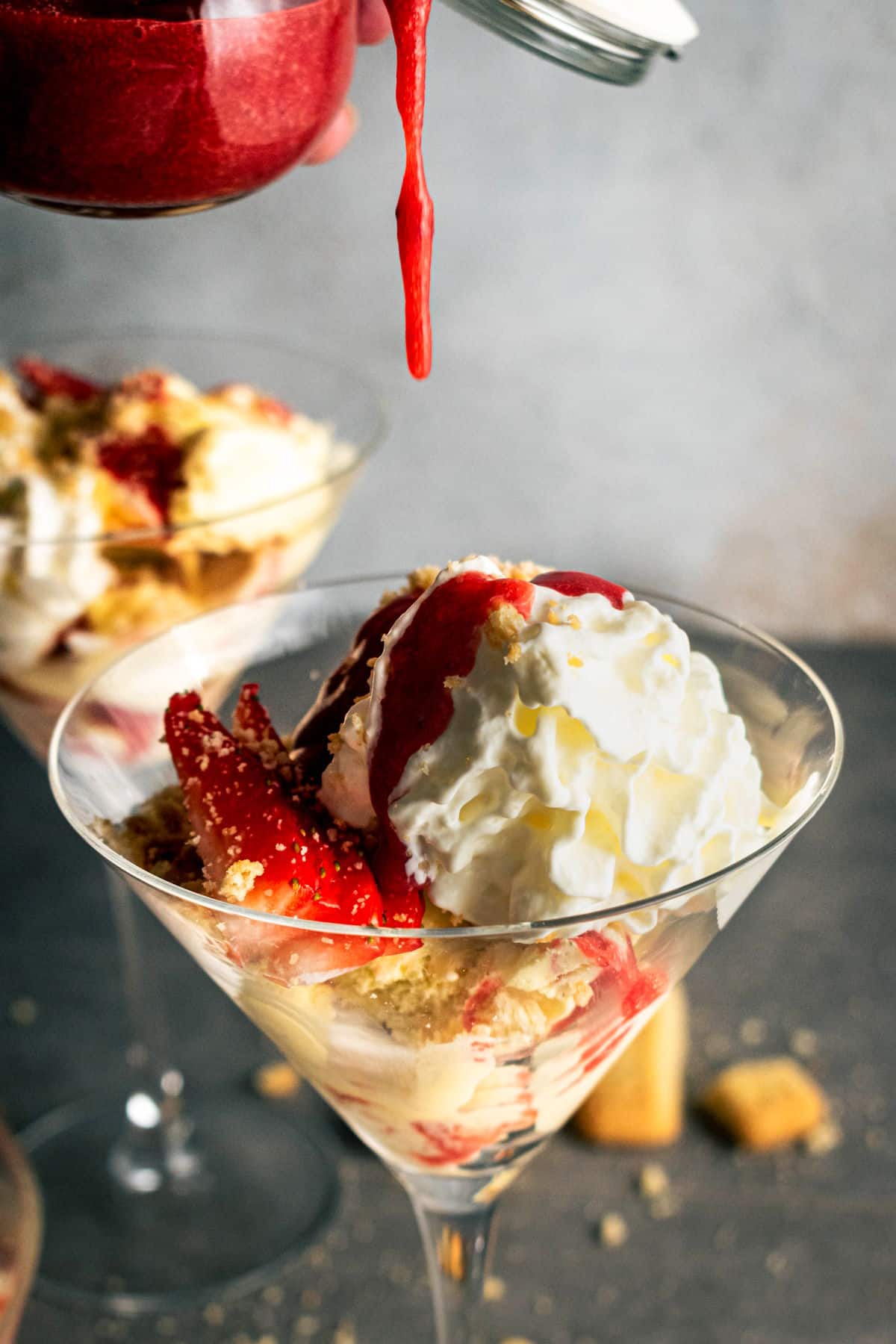 Strawberry shortcake ice cream in a martini glass with strawberry syrup drizzled on top.