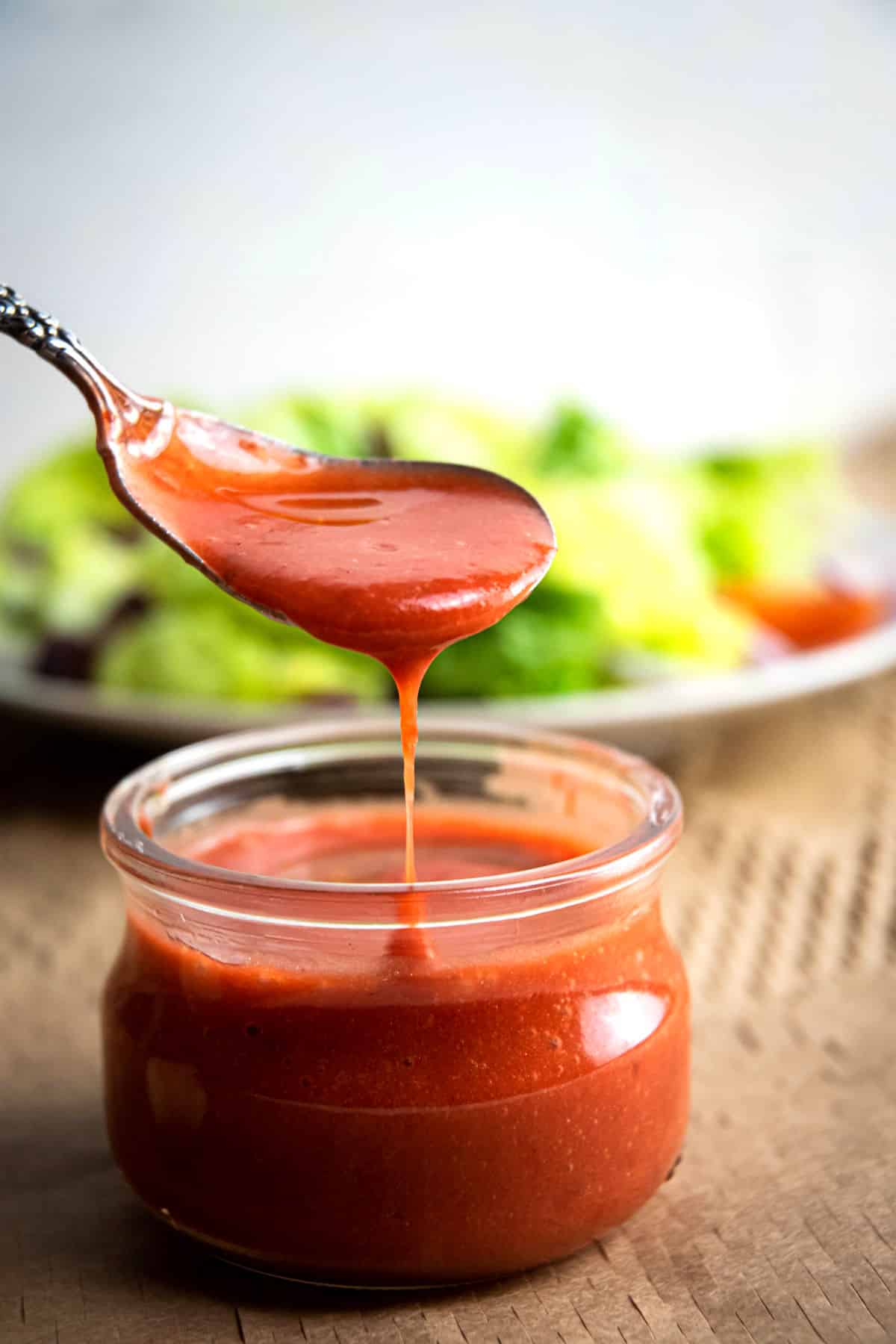 Strawberry vinaigrette drizzling from spoon into jar.